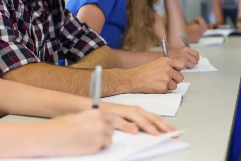 Varios estudiantes sentados en una mesa larga tomando apuntes en sus cuadernos durante las prácticas profesionales en nuestra Fundación